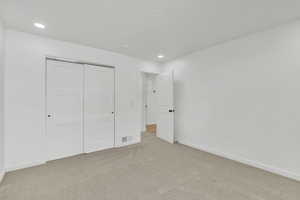 Unfurnished bedroom featuring light colored carpet and a closet