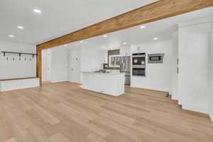 Unfurnished living room with beamed ceiling and light hardwood / wood-style floors