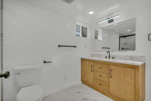 Bathroom featuring vanity, a shower with shower door, and toilet