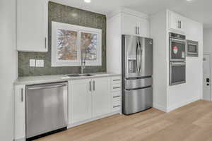 Kitchen featuring appliances with stainless steel finishes, light stone countertops, sink, and white cabinets