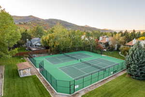 View of sport court with a mountain view and a yard