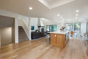 Kitchen featuring a breakfast bar, sink, hanging light fixtures, a kitchen island with sink, and light hardwood / wood-style flooring