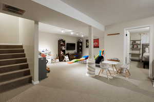 Game room with rail lighting, carpet, and a textured ceiling