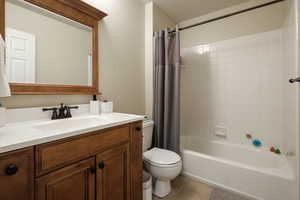 Full bathroom featuring tile patterned floors, toilet, shower / bath combo with shower curtain, and vanity