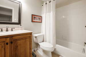 Full bathroom with vanity, shower / bath combination with curtain, and toilet