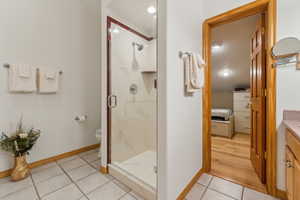 Bathroom with an enclosed shower, vanity, tile patterned floors, and toilet