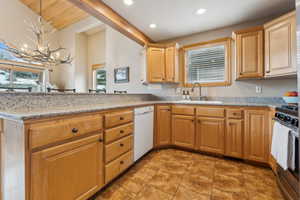 Kitchen featuring decorative light fixtures, dishwasher, sink, light stone counters, and stainless steel gas range