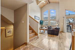 Stairway with hardwood / wood-style floors, high vaulted ceiling, ceiling fan, wooden ceiling, and beam ceiling