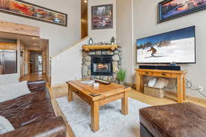 Living room with a stone fireplace and light hardwood / wood-style floors