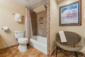 Bathroom featuring shower / tub combo, tile patterned flooring, a textured ceiling, and toilet