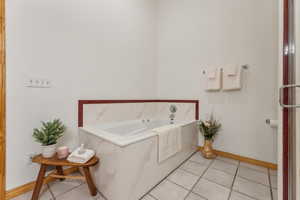 Bathroom with tile patterned floors and a tub to relax in