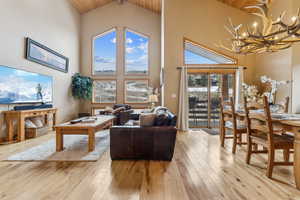 Living room featuring plenty of natural light, a chandelier, high vaulted ceiling, and light hardwood / wood-style flooring