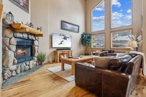 Living room featuring hardwood / wood-style flooring, a towering ceiling, and a fireplace