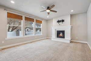 Unfurnished living room featuring carpet floors and ceiling fan