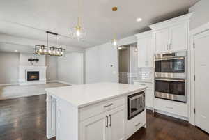 Kitchen with white cabinetry, stainless steel appliances, a center island, and hanging light fixtures