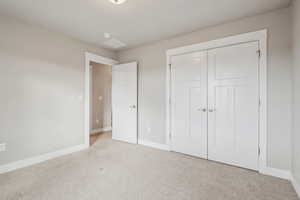 Unfurnished bedroom featuring light colored carpet and a closet