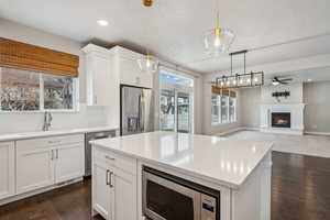 Kitchen featuring dark hardwood / wood-style floors, decorative light fixtures, white cabinetry, sink, and stainless steel appliances