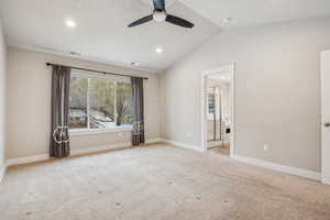 Spare room featuring lofted ceiling, light carpet, and ceiling fan