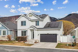 View of front of house with a mountain view, a garage, and solar panels