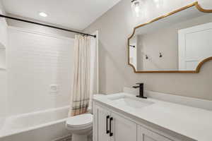 Full bathroom with shower / bathtub combination with curtain, vanity, and toilet