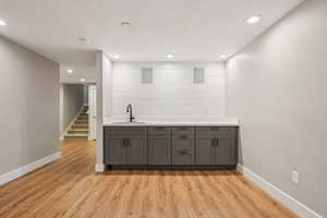 Bar featuring gray cabinets, sink, and light hardwood / wood-style flooring