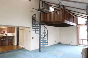 Staircase featuring beam ceiling, ceiling fan, and high vaulted ceiling