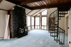 Unfurnished living room with carpet floors, wooden ceiling, lofted ceiling with beams, and a wood stove