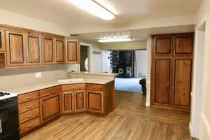 Kitchen featuring sink, light hardwood / wood-style floors, gas stove, and kitchen peninsula