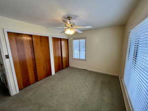 Unfurnished bedroom featuring carpet flooring, two closets, and ceiling fan