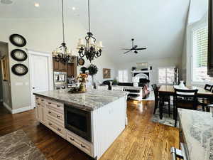 Kitchen featuring built in microwave, dark hardwood / wood-style floors, a center island, and pendant lighting