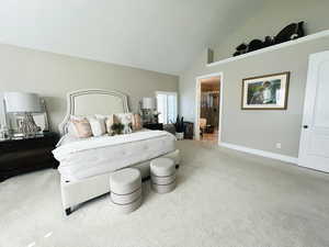 Carpeted bedroom featuring high vaulted ceiling and ensuite bathroom