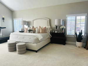 Carpeted bedroom with vaulted ceiling and multiple windows