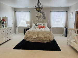 Bedroom with light colored carpet and a chandelier