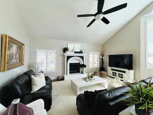 Living room featuring vaulted ceiling, plenty of natural light, and ceiling fan