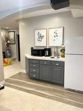 Bar with gray cabinetry, sink, and white refrigerator