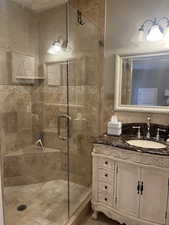 Bathroom with vanity, a shower with door, and tile walls