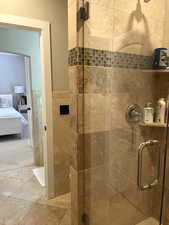 Bathroom featuring tile walls and a shower with door