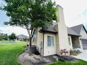 Exterior space featuring cooling unit, a garage, and a lawn