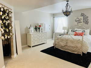 Carpeted bedroom featuring an inviting chandelier