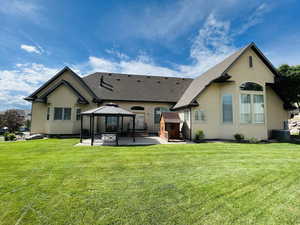 Rear view of property featuring a gazebo, a patio, central AC unit, and a lawn