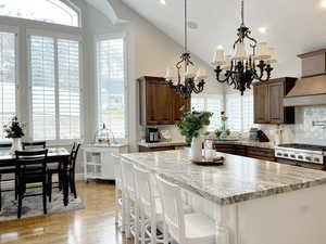 Kitchen with light stone counters, light hardwood / wood-style flooring, a chandelier, and a kitchen island