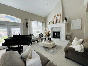 Living room featuring a tiled fireplace, light carpet, high vaulted ceiling, and french doors