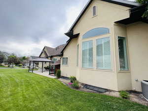 View of side of home with a gazebo, a yard, and central AC unit