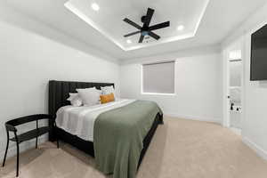 Bedroom with ceiling fan, a raised ceiling, and light carpet