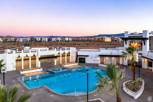 Pool at dusk featuring a hot tub and a mountain view