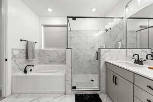 Bathroom featuring vanity, separate shower and tub, and tile walls