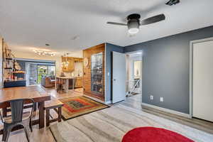 Living room featuring sink, ceiling fan, a textured ceiling, and light wood-type flooring