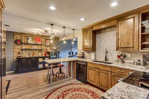 Kitchen with pendant lighting, dishwasher, sink, a breakfast bar area, and kitchen peninsula