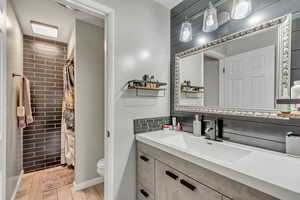 Bathroom featuring tasteful backsplash, vanity, toilet, and hardwood / wood-style floors