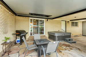 View of patio with area for grilling and a hot tub